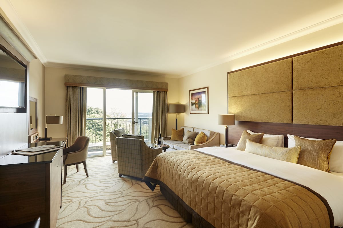 A hotel room with a large bed, a desk, a chair, and a sofa.