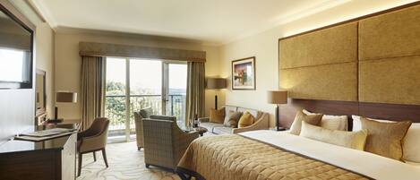 A hotel room with a large bed, a desk, a chair, and a sofa.