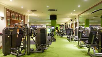 A gym with various exercise machines and a green carpeted floor.