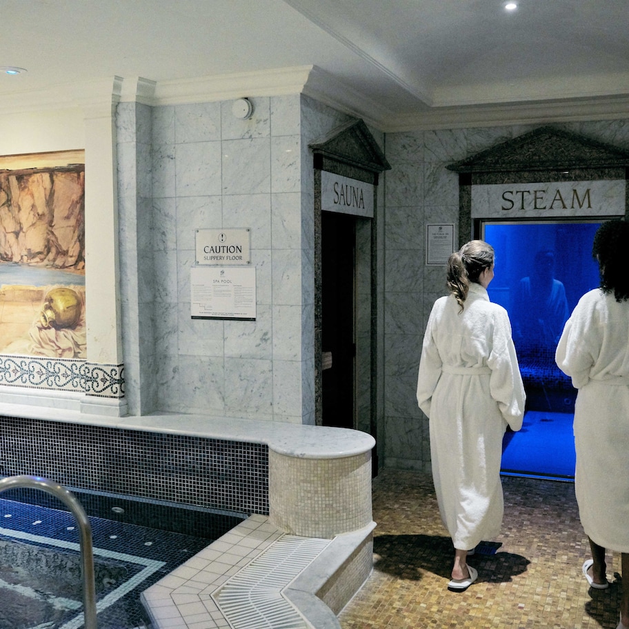 A spa area with a sauna and steam room, a tiled floor, and a pool with a metal ladder.