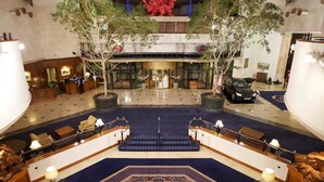 A spacious lobby with a central staircase, seating areas, and a reception desk. - Celtic Manor Resort (Newport)