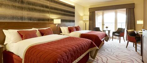 A hotel room with two beds, a desk, and a chair.
