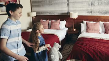 Habitación de hotel con dos camas, una colcha a cuadros rojos y blancos, y un cabecero de madera.