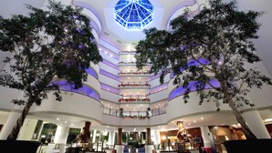 A multi-level atrium with a central skylight, multiple balconies, and indoor trees. - Celtic Manor Resort (Newport)