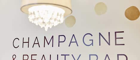 A sign for a Champagne & Beauty Bar with a chandelier above it.