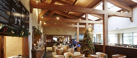 A spacious lobby with high wooden ceilings, a Christmas tree, and seating areas.
