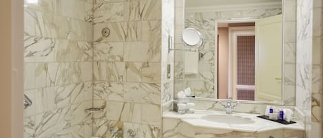 A bathroom with a marble-tiled wall, a bathtub, a sink with a mirror, and a towel rack.