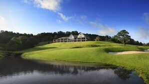 A golf course with a clubhouse, a pond, and rolling green hills. - Celtic Manor Resort (Newport)