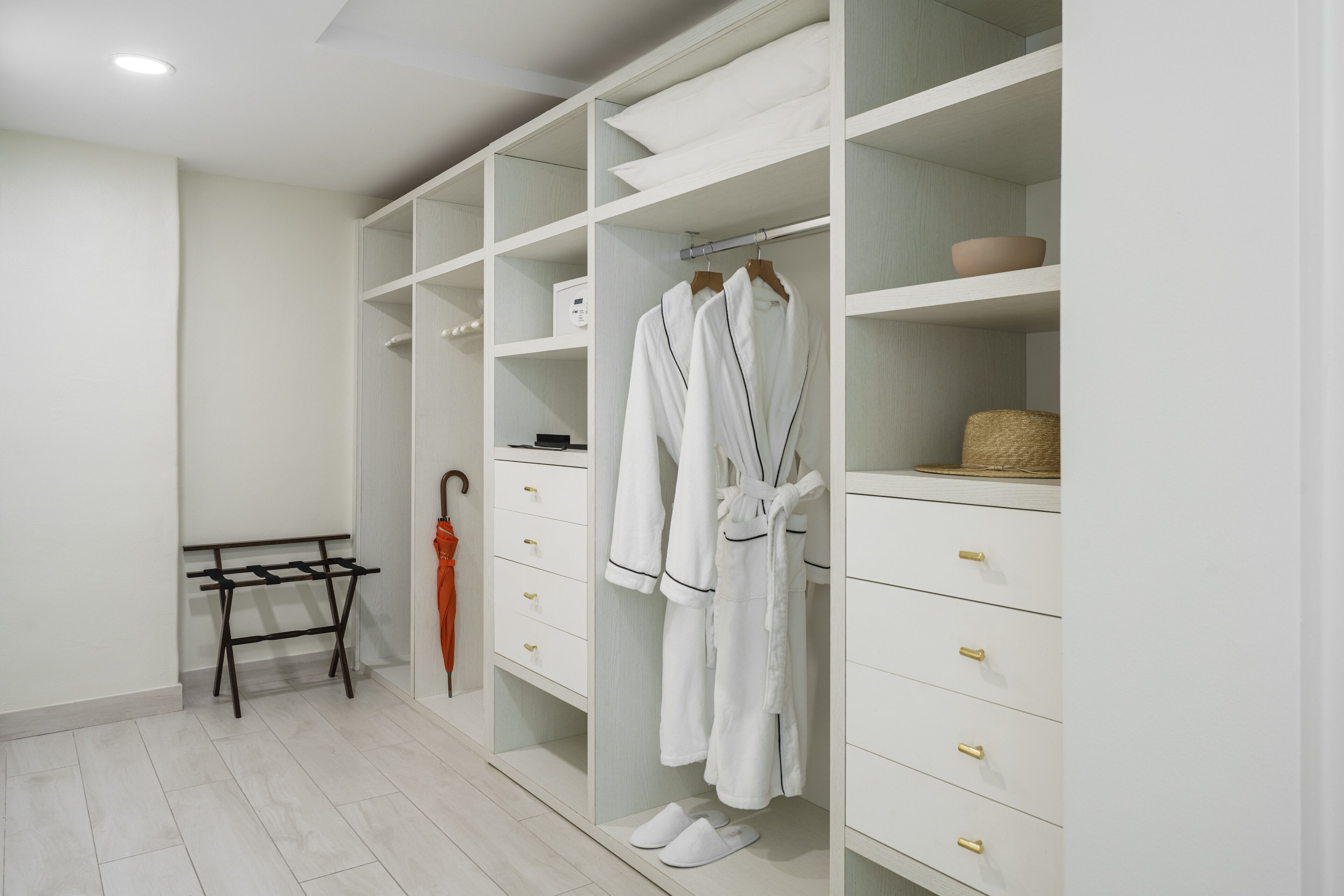 Un vestidor con estantes blancos, un tendedero y una cesta.