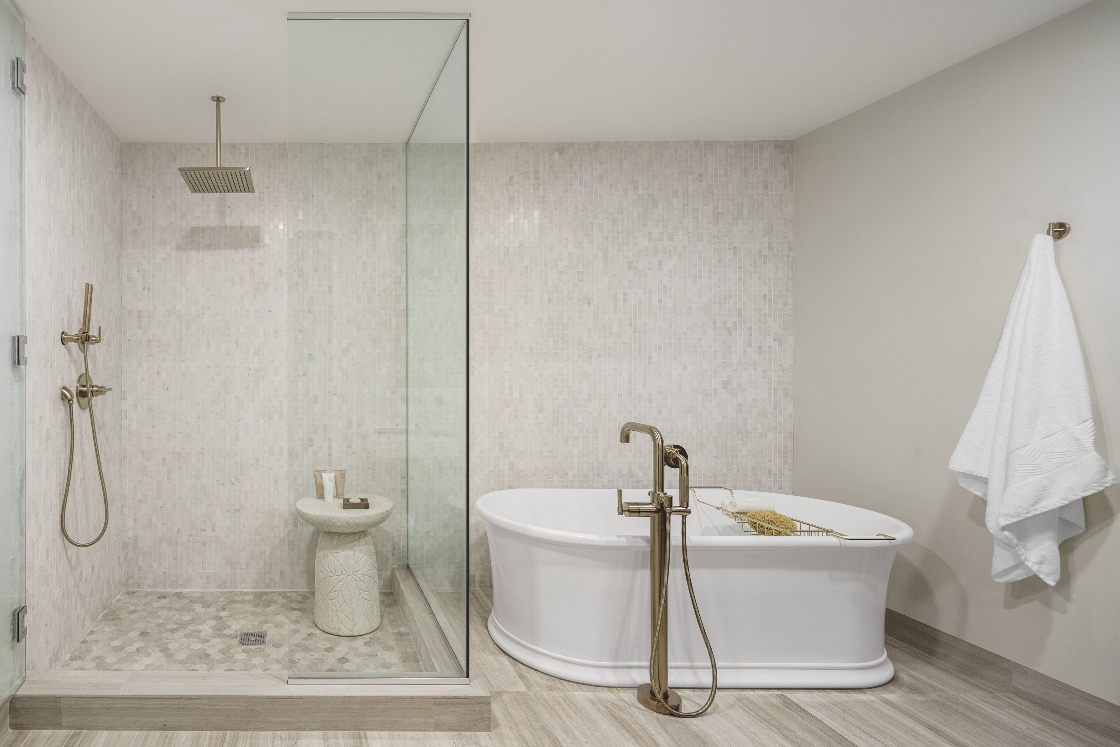 A modern bathroom with a glass-enclosed shower, a freestanding bathtub, and a pedestal sink.