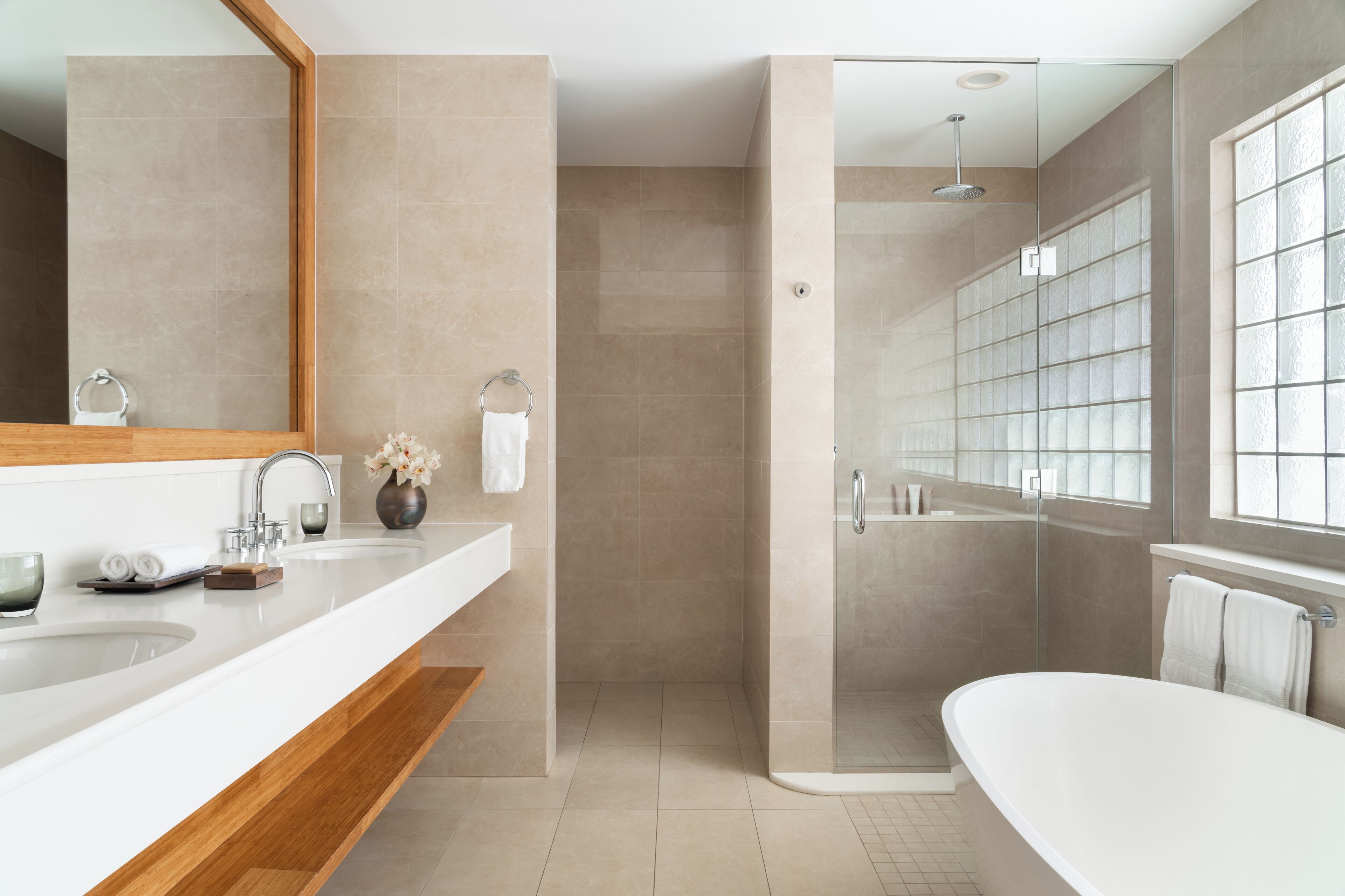 Un baño moderno con un espejo grande, dos lavamanos, una ducha y una bañera.
