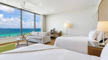 Habitación de hotel con dos camas, un sofá, un escritorio y vista al océano.