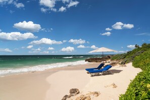 Am Strand, weißer Sandstrand, Liegestühle, Sonnenschirme