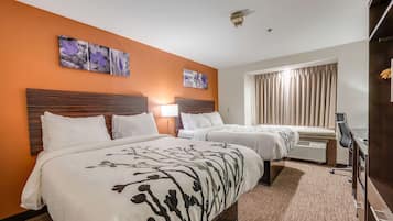 A hotel room with two beds, a desk, a chair, and a window with curtains.