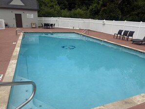 A rectangular swimming pool with a white fence, a pool ladder, and a few lounge chairs. - Sleep Inn & Suites Decatur West (Decatur)