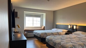 A hotel room with two beds, a desk, a window, and a wall-mounted TV. - Motel 6 Indianapolis Carmel (Indianapolis)