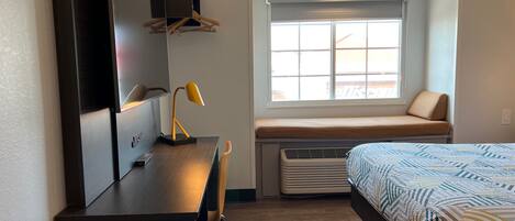 Un dormitorio moderno con cama, escritorio y ventana.