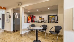 A small café area with a round table and four chairs, vending machines, and a refrigerator. - Motel 6 Indianapolis Carmel (Indianapolis)