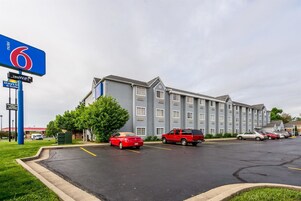 Un motel con un edificio amplio, un estacionamiento y varios coches.