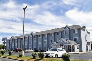A multi-story hotel with a row of rooms, a parking lot, and a small building with a covered entrance. - Motel 6 Indianapolis Carmel (Indianapolis)