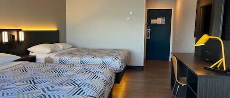Habitación de hotel con dos camas, un escritorio, una silla y un espejo.