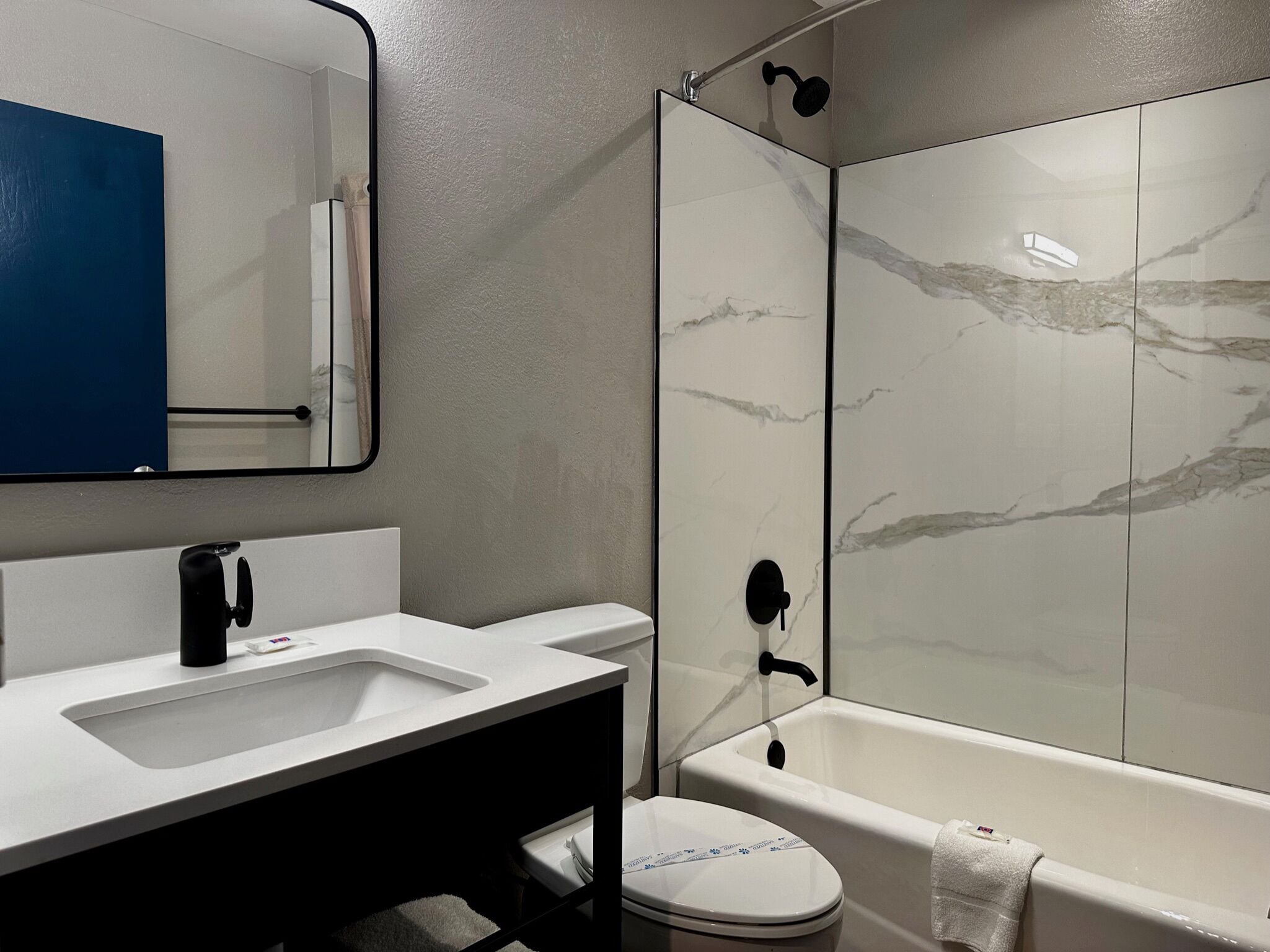 A modern bathroom with a white sink, mirror, and toilet.