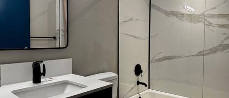 A modern bathroom with a white sink, mirror, and toilet.
