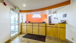 A reception area with a wooden reception desk, a "No Smoking" sign, and a "Employees Only" sign. - Motel 6 Indianapolis Carmel (Indianapolis)