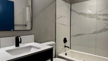 A modern bathroom with a white sink, a toilet, and a glass-enclosed shower area.