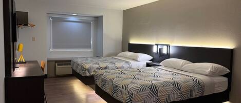 A modern hotel room with two beds, a desk, and a large window.
