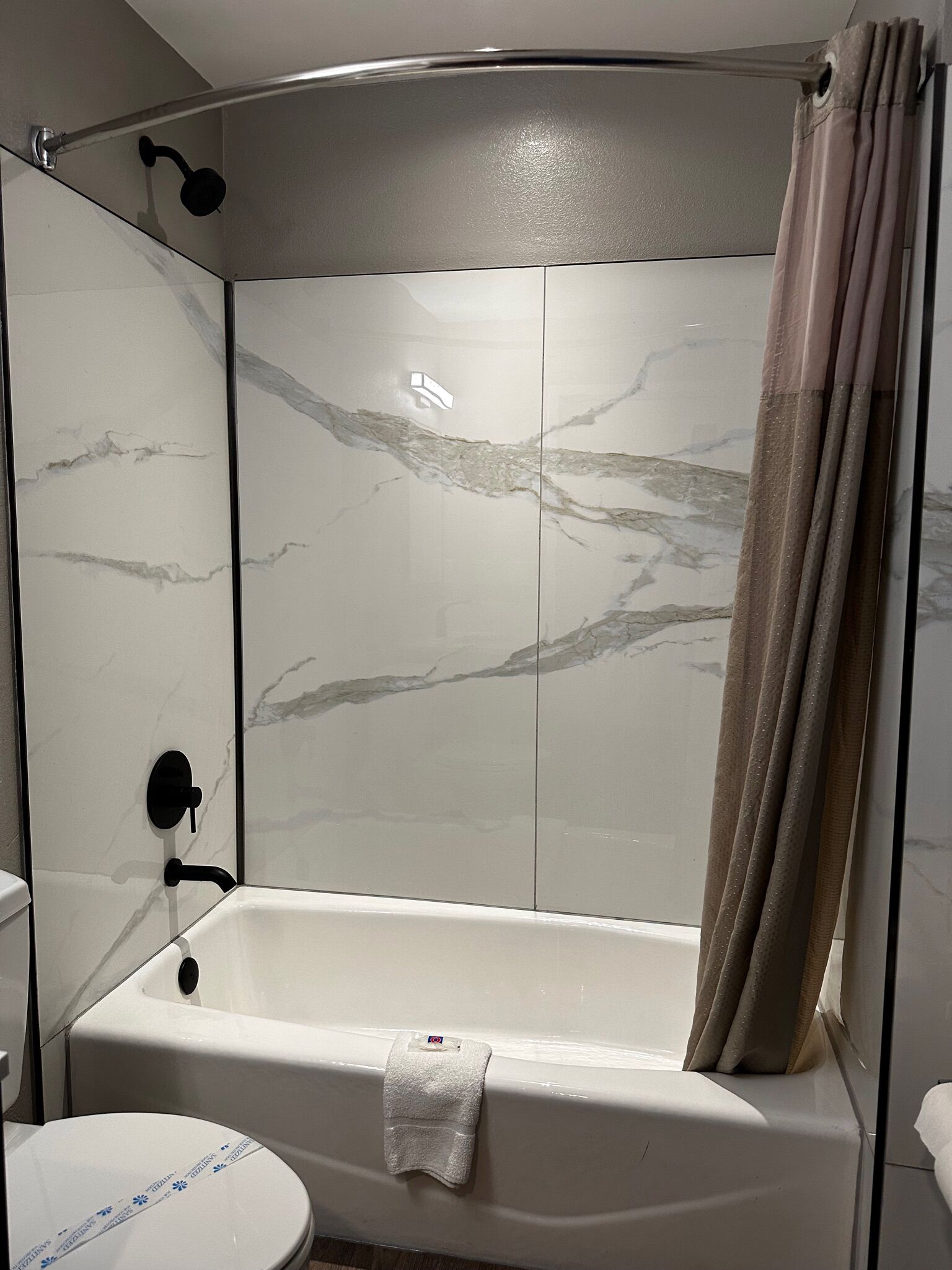 A bathroom with a glass-enclosed shower, a white bathtub, and a toilet.