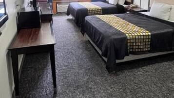 A hotel room with two beds, a desk, and a window with curtains.