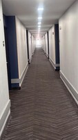 Un pasillo largo y estrecho en un hotel, con puertas a ambos lados y piso alfombrado.