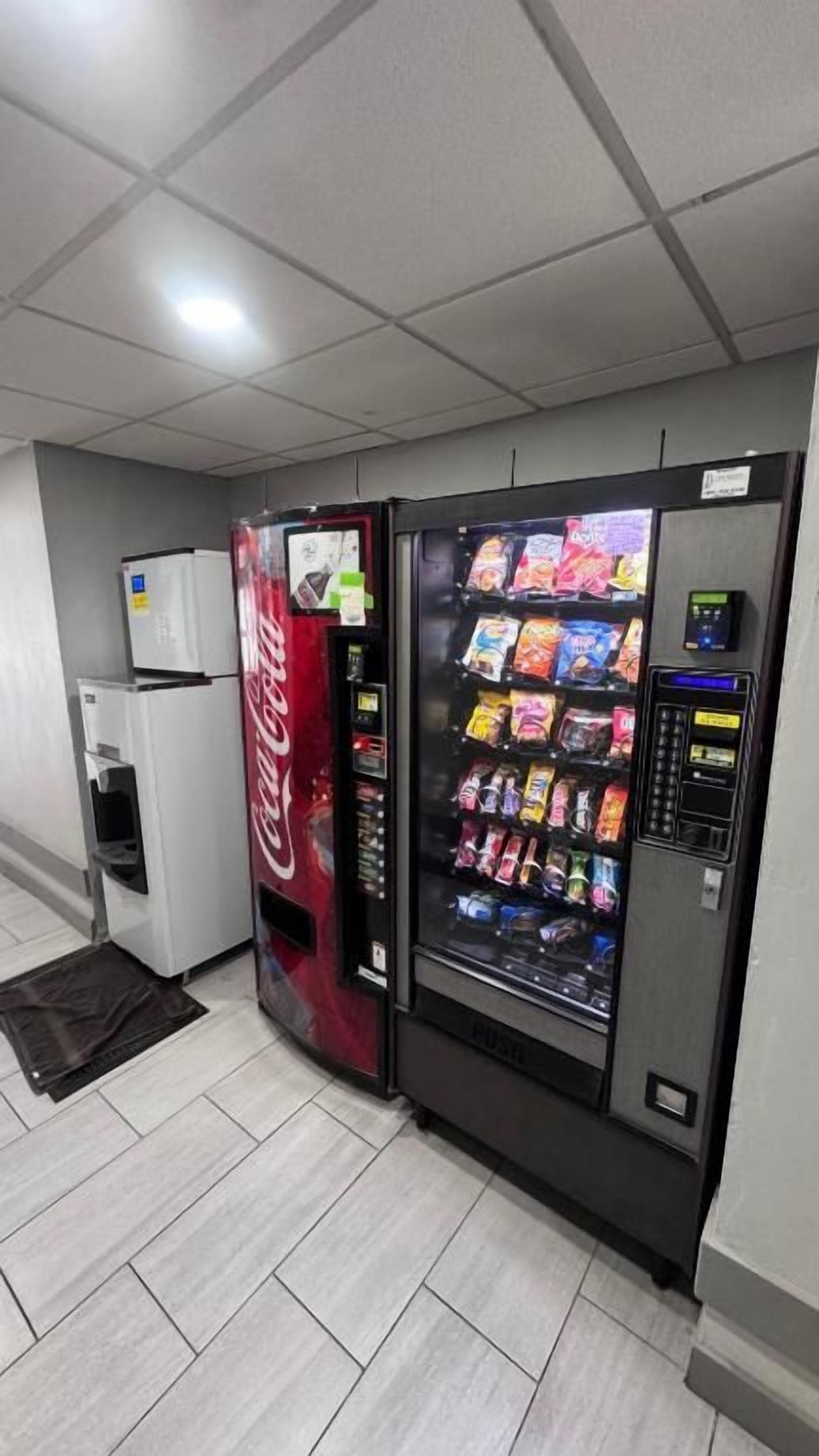 Zona de máquinas expendedoras con una máquina de Coca-Cola y otra de aperitivos.