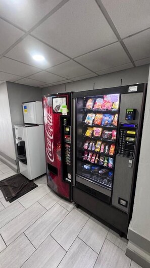 Espaço com máquinas de venda automática, incluindo uma máquina de Coca-Cola e outra de lanches.
