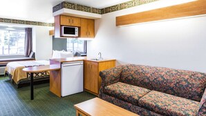 Une pièce de taille modeste comprenant un lit, une petite kitchenette, un canapé et une table.
