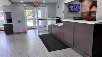 Una zona de recepción con mostrador, televisor y puerta que da a otra habitación.