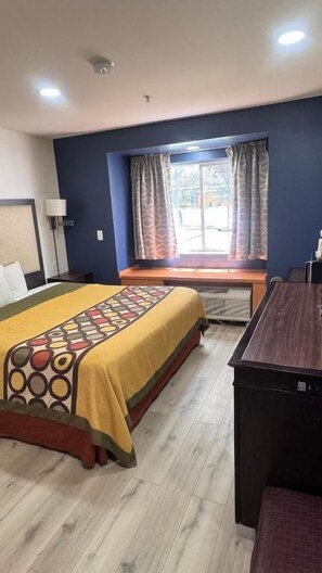 Una habitación de hotel con cama, escritorio y ventana con cortinas.