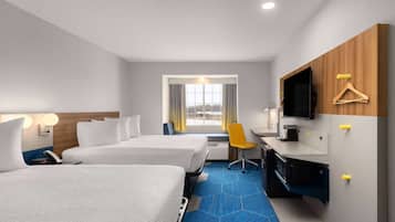 A hotel room with two beds, a desk with a chair, a television, and a window with curtains.