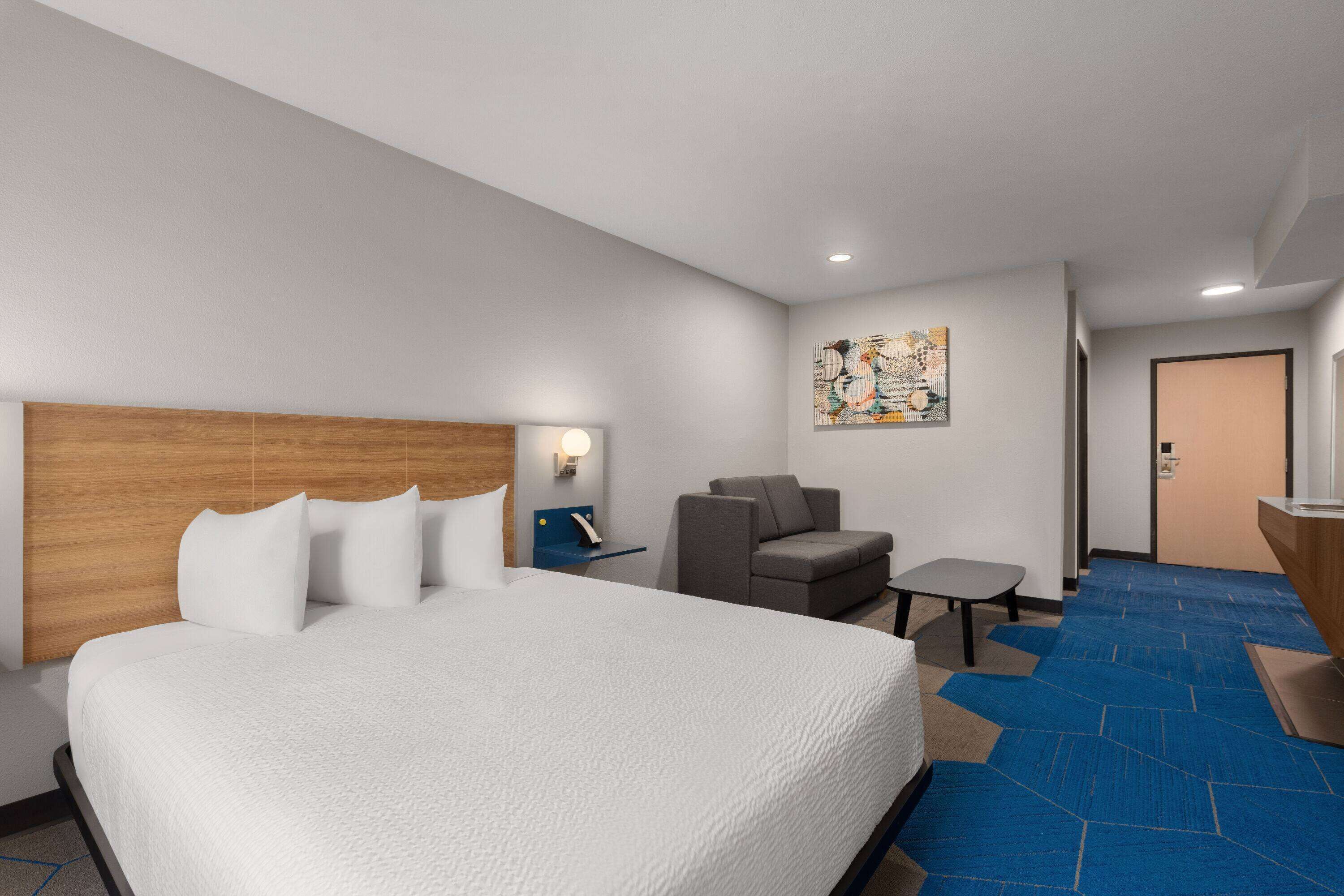 Una habitación de hotel con una cama grande, un escritorio, una silla y una mesita.
