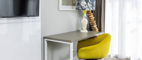 A modern office desk with a yellow chair, a white vase, and a lamp with a blue and black patterned shade.