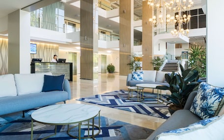A spacious lobby with a reception desk, seating area, and a staircase leading to upper floors.