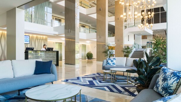 Un vestíbulo amplio con mostrador de recepción, zona de estar y una escalera que conduce a los pisos superiores.
