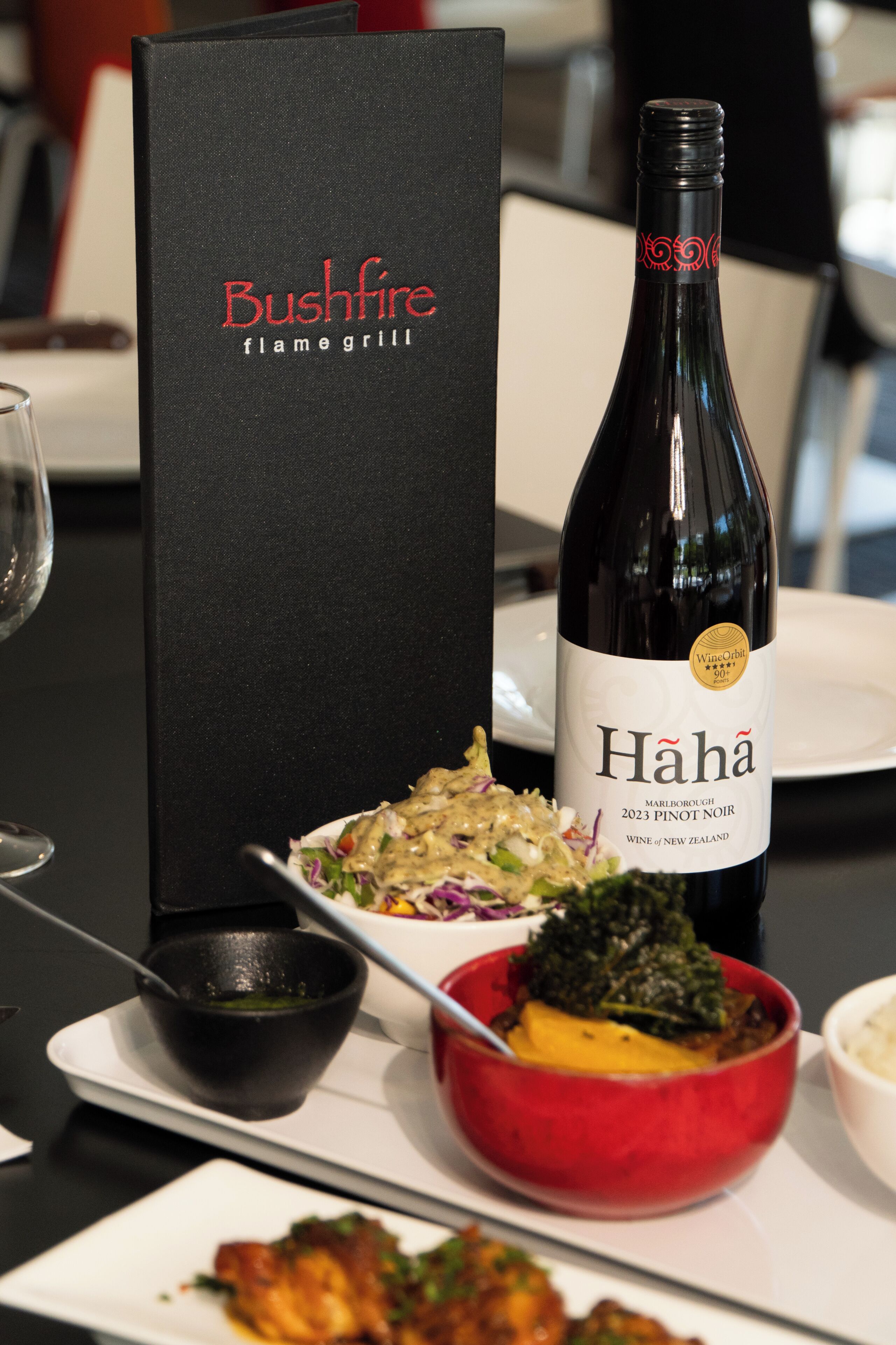 A bottle of Hahā wine, a menu, and a plate of food.