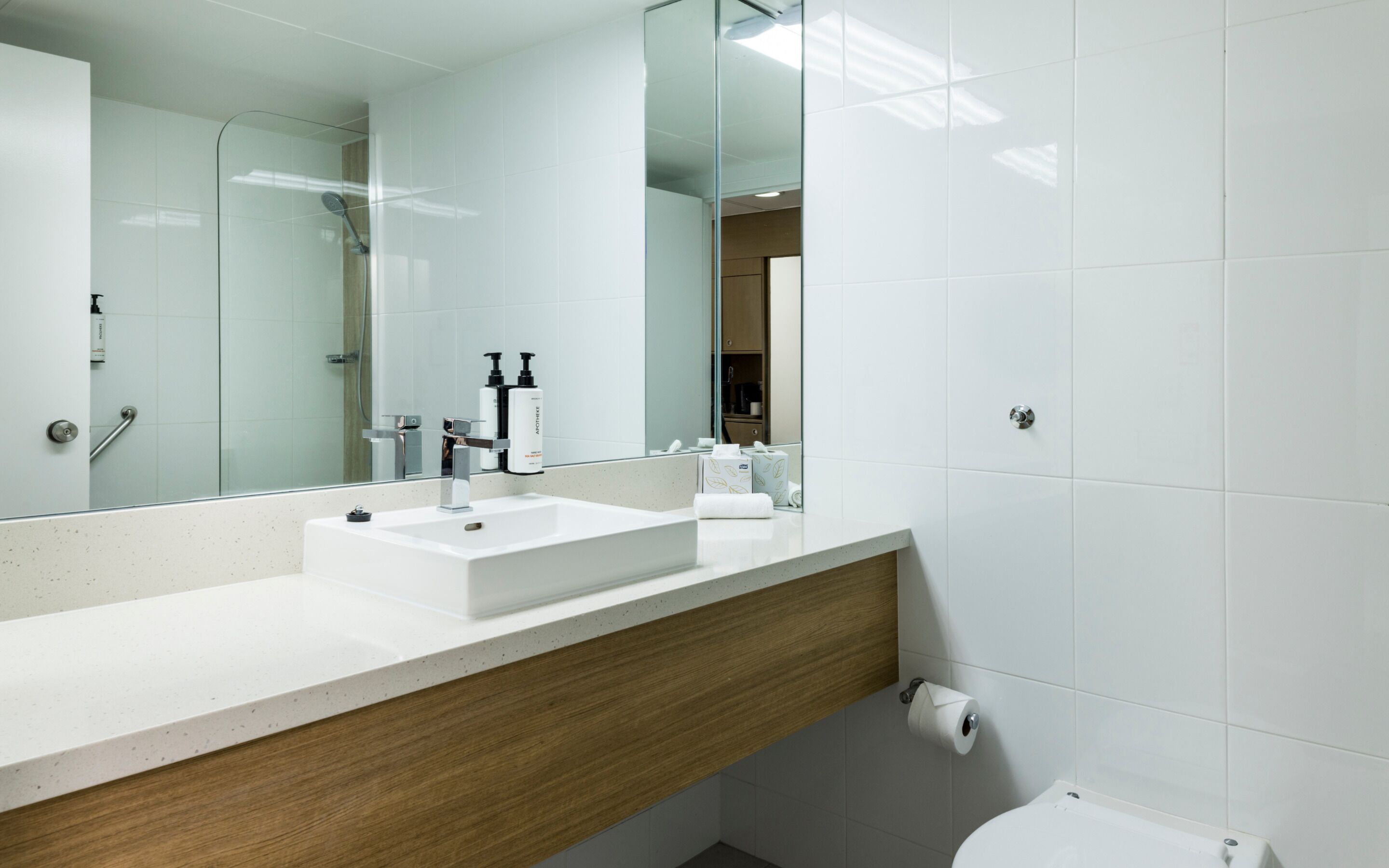 A modern bathroom with a white sink, mirror, and toilet.