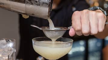 Una persona vertiendo un líquido desde un coctelera en un vaso.