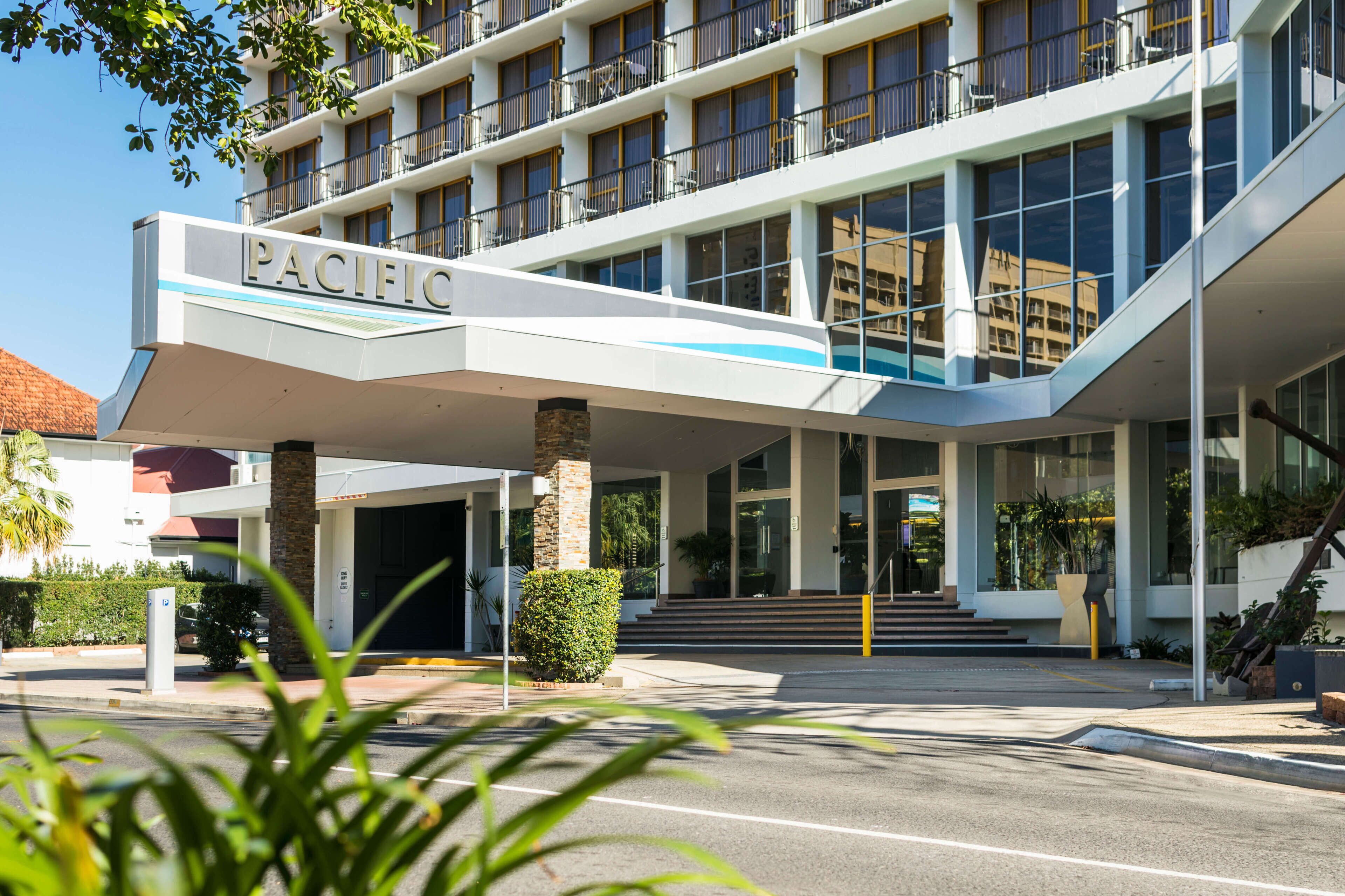 A modern hotel with a prominent "PACIFIC" sign, a covered entrance, and a staircase leading to the main building.