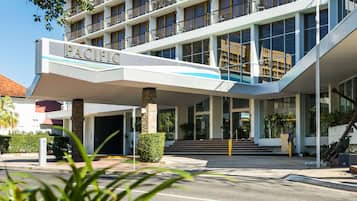 A modern hotel with a prominent "PACIFIC" sign, a covered entrance, and a staircase leading to the main building.
