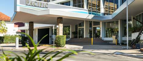 A modern hotel with a prominent "PACIFIC" sign, a covered entrance, and a staircase leading to the main building.