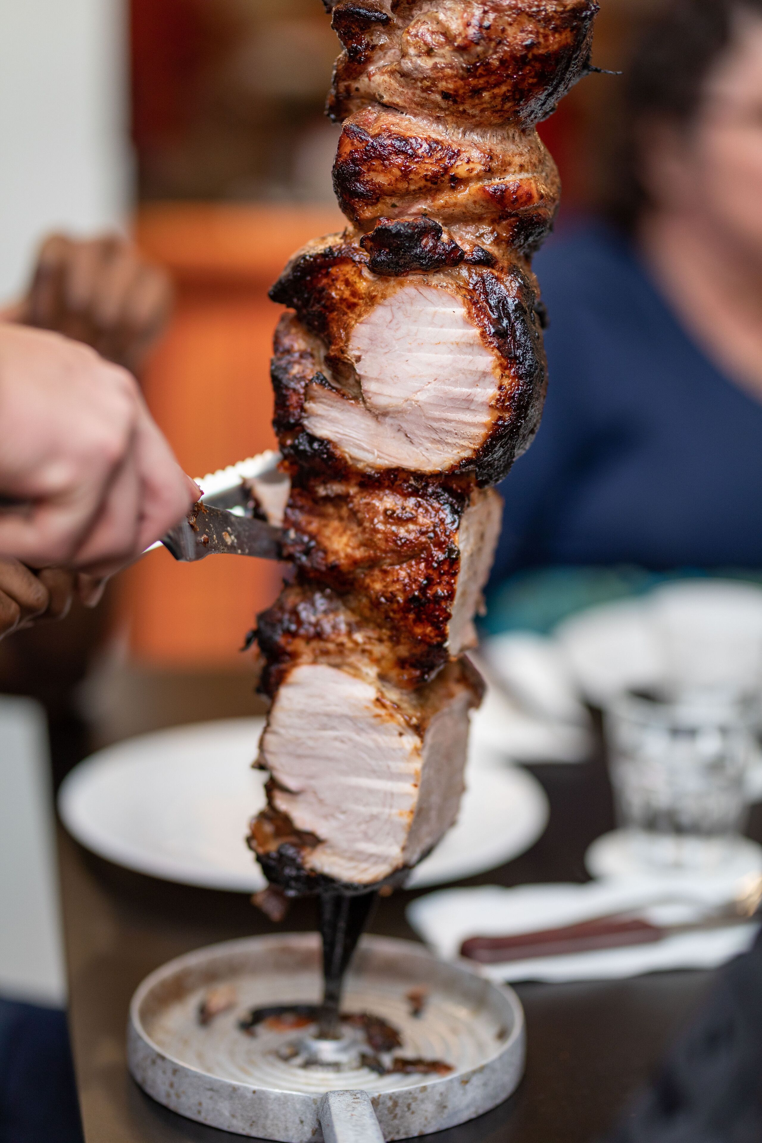 A vertical rotisserie with meat being carved.